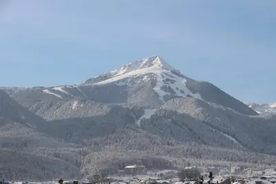 a snow covered mountain in front of a city at Hotel Alpin - 91 Bansko in Bansko