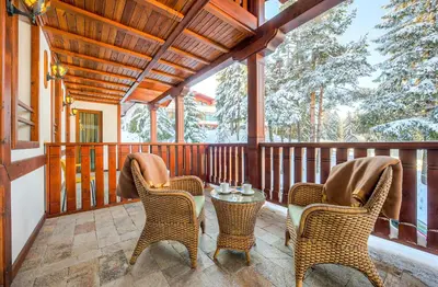 a screened porch with two chairs and a table at MPM Family Hotel Merryan in Pamporovo
