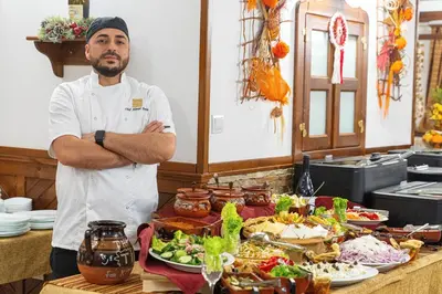 a chef standing in front of a table of food at MPM Family Hotel Merryan in Pamporovo
