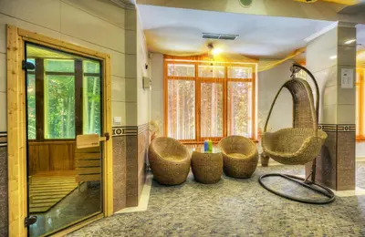 a bathroom with wicker chairs and a tub and a mirror at MPM Family Hotel Merryan in Pamporovo