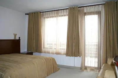 a bedroom with a bed and two large windows at Guest House Chicho Tsane in Bansko