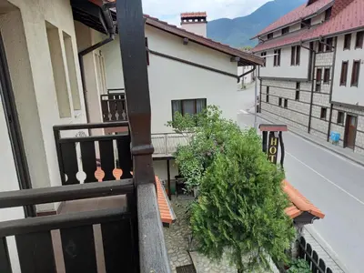 a balcony of a house with a bench on a street at Guest house Skabrin in Bansko