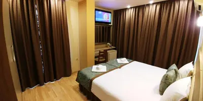 a hotel room with a bed and a flat screen tv at Garden Guest House in Sandanski