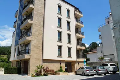 a white building with cars parked in front of it at Garden Guest House in Sandanski