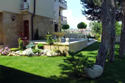 a garden with a fountain and a bench in a yard at Garden Guest House in Sandanski