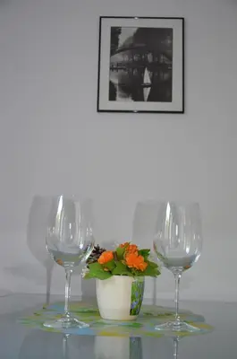two wine glasses and a vase with a flower on a table at Bulhotel Pritzker Apartment in Sofia