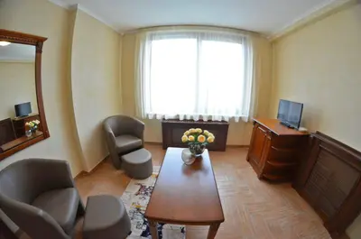 a living room with a table and chairs and a television at Central West Hotel in Sofia