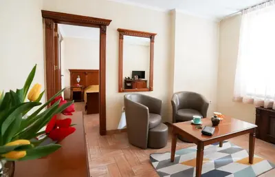 a living room with a table and chairs and a mirror at Central West Hotel in Sofia