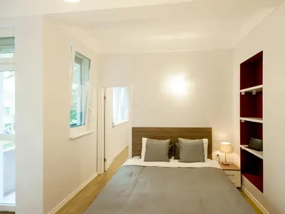 a white bedroom with a bed and a window at Solunska Apartment in Sofia