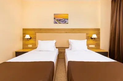 two beds in a hotel room with two lamps at Hotel Intelcoop in Plovdiv