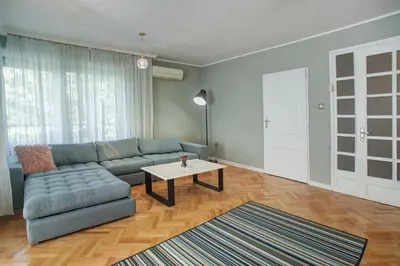 a living room with a blue couch and a table at Spacious flat close to the American Embassy, free parking place in Sofia
