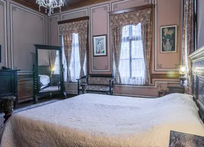 a bedroom with a large bed and two windows at Old Legends Hotel in Plovdiv