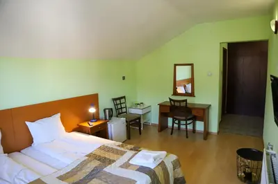 a hotel room with a bed and a desk and a desk at Къща за гости Типик in Bansko