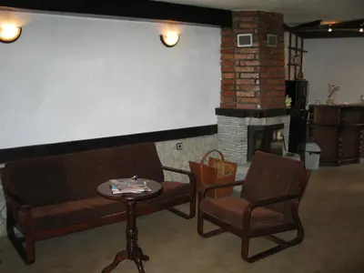 a living room with two benches and a fireplace at Къща за гости Типик in Bansko