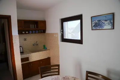 a kitchen with a window and a table and chairs at Къща за гости Типик in Bansko