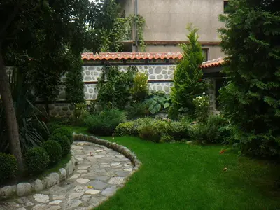 a garden with a stone path in front of a building at Къща за гости Типик in Bansko