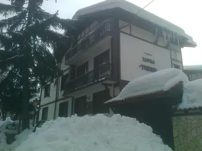 a building with a pile of snow in front of it at Къща за гости Типик in Bansko