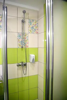 a bathroom with a shower with green and white tiles at Visito Aparthouse in Sofia