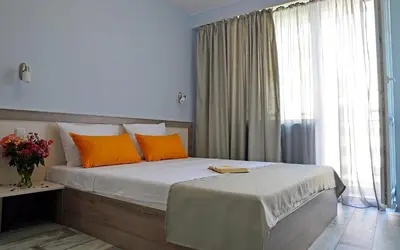 a bedroom with a bed with orange pillows and a window at Visito Aparthouse in Sofia