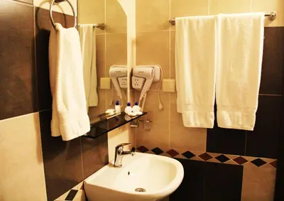 a bathroom with a sink and a toilet and towels at Hotel Diavolo in Sofia