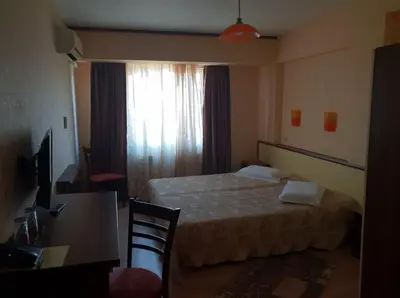 a hotel room with a bed and a desk and a window at Hotel Diavolo in Sofia