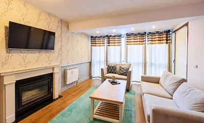 a living room with a fireplace and a tv at Predela 2 Aparthotel in Bansko