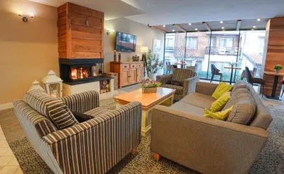 a living room with three couches and a fireplace at Predela 2 Aparthotel in Bansko