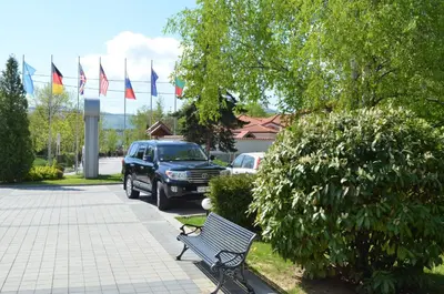 a car parked in a parking lot with a bench and flags at Hotel Bankya Palace in Bankya