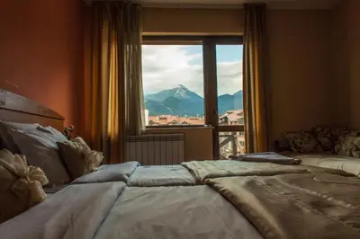 a bedroom with a large window with a mountain view at Pirina Club Hotel in Bansko