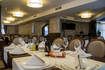 a dining room with tables and chairs with wine glasses at Family Hotel Delta in Ognyanovo