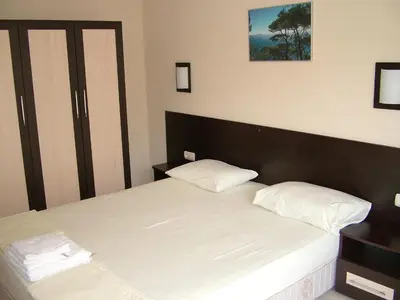 a bedroom with a bed with white sheets and pillows at Family Hotel Delta in Ognyanovo