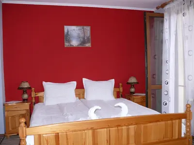 a bedroom with a red wall and a bed with swans on it at Kashta Peychevi in Govedartsi