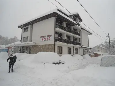a person standing in the snow in front of a building at Family hotel Iskar in Govedartsi