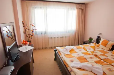 a bedroom with a large bed and a window at Family hotel Iskar in Govedartsi