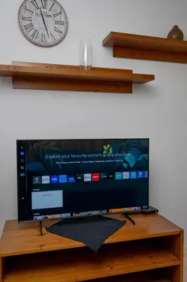 a flat screen tv with a clock on a wall at St. John Hill Apartment, Bansko in Bansko