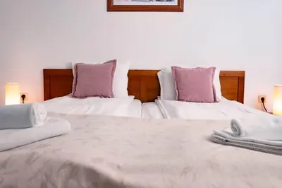 a bedroom with two beds with white sheets and purple pillows at St. John Hill Apartment, Bansko in Bansko