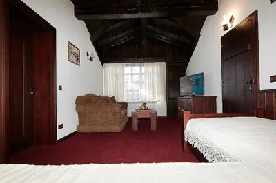 a bedroom with a bed and a chair and a television at Family hotel Makedonska Kruchma in Dobrinishte