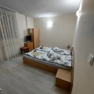 a bedroom with a bed and a television in it at Guesthouse Pumpalovi in Dobrinishte