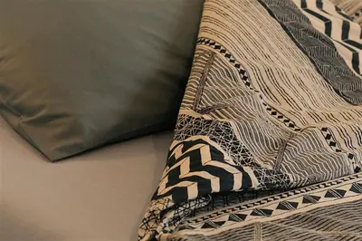 a blanket laying on a bed next to a pillow at St. Seraphim's Apartment in Sofia