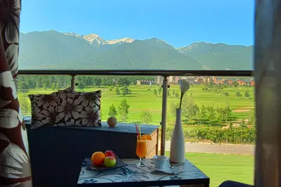 a balcony with a table with a view of the mountains at Cornelia Deluxe Residence in Bansko