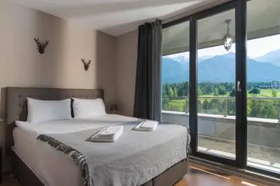 a bedroom with a bed and a large window at Cornelia Deluxe Residence in Bansko