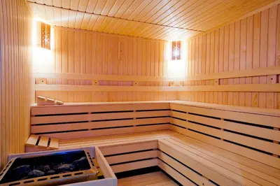 a sauna with wooden walls and a tub in it at Cornelia Deluxe Residence in Bansko