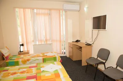 a room with two beds and a desk and two chairs at Hotel Deva in Sandanski