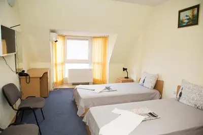 a hotel room with two beds and a desk at Hotel Deva in Sandanski