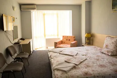 a bedroom with a bed and chairs and a window at Hotel Deva in Sandanski