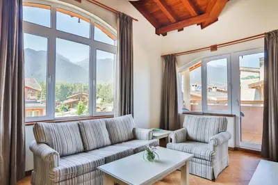 a living room with two couches and a table at Pirin Golf & Country Club Apartment Complex in Bansko