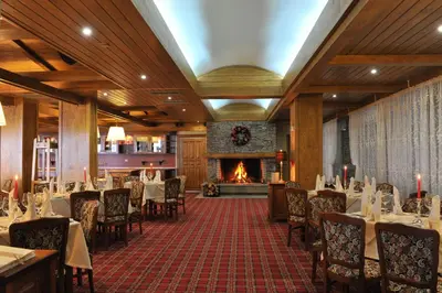 a restaurant with tables and chairs and a fireplace at Pirin Golf & Country Club Apartment Complex in Bansko