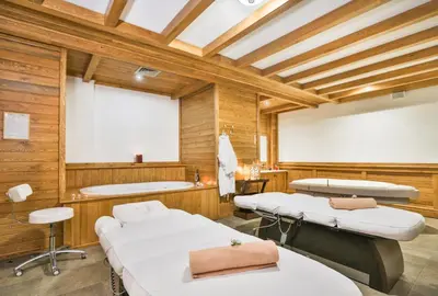 two beds in a room with wooden walls at Pirin Golf & Country Club Apartment Complex in Bansko