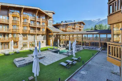 a hotel with a courtyard with umbrellas and chairs at Pirin Golf & Country Club Apartment Complex in Bansko