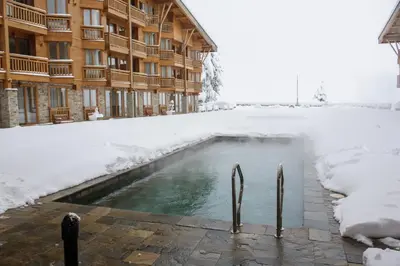 a swimming pool in the snow in front of a building at Pirin Golf & Country Club Apartment Complex in Bansko